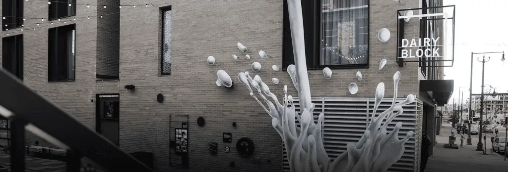 sculpture of milk splashing up corner of brick building