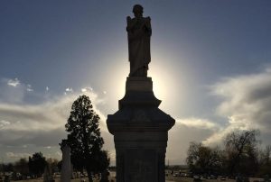 graveyard statue silhouetted by sunset